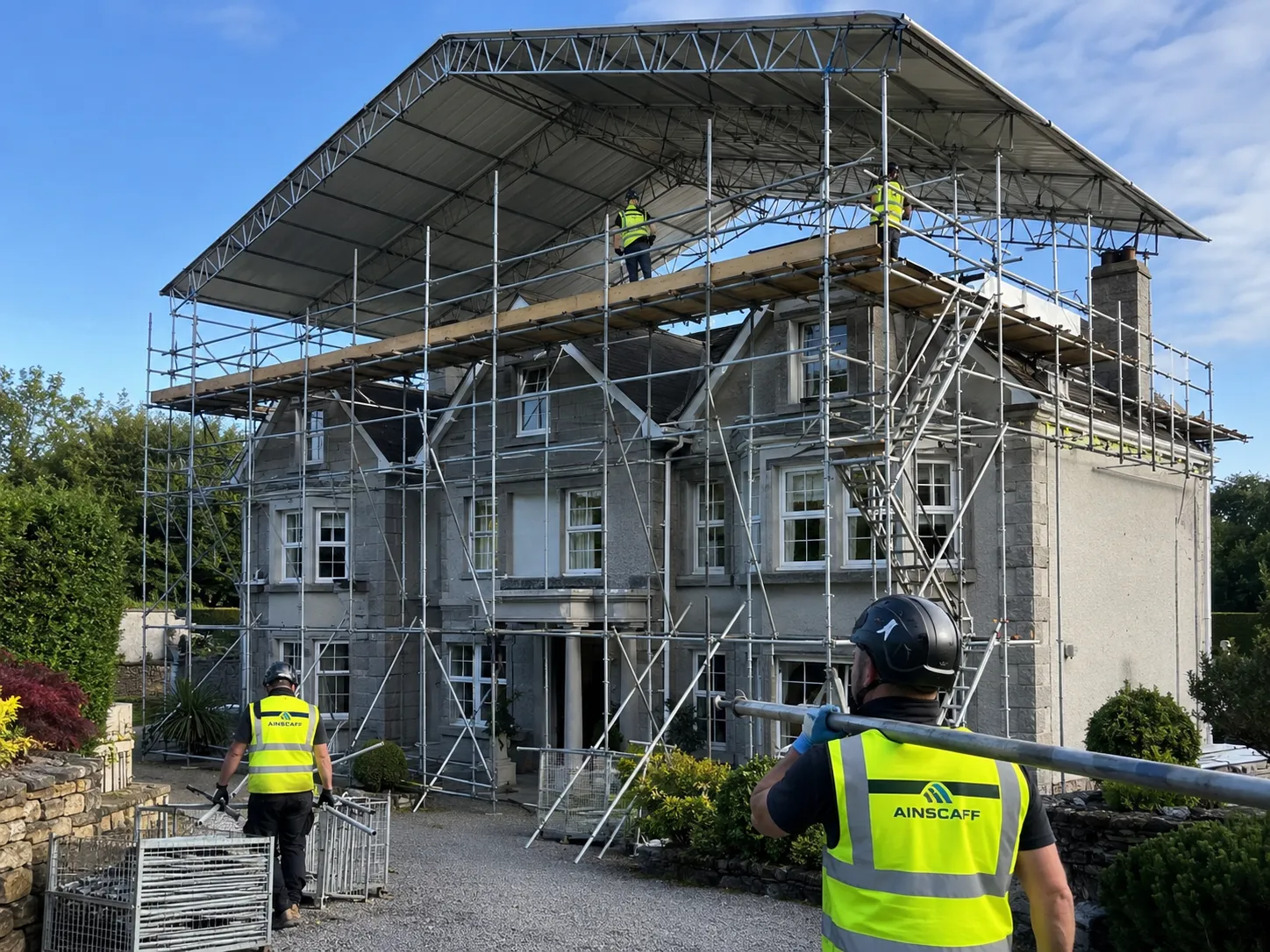 A wide 6m to 9m span temporary roof scaffold structure erected by Ainscaff operatives over a larger detached house.