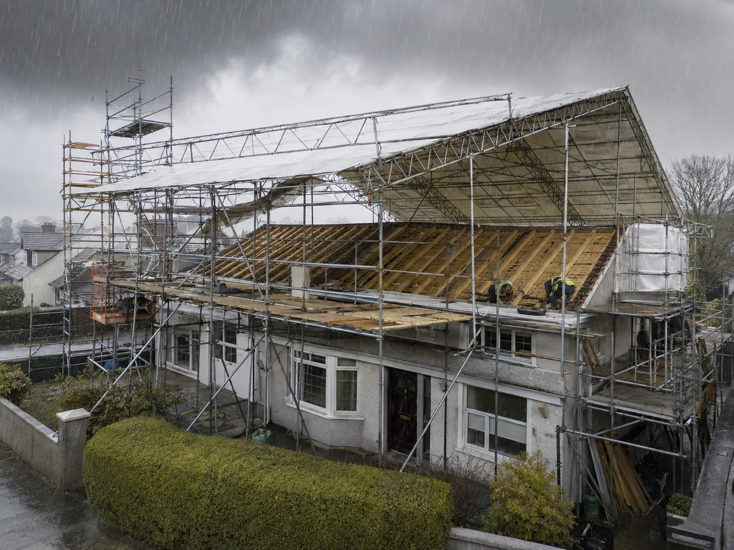 A temporary roof scaffold installed over a full residential re-roofing project to protect the fully exposed roof deck from heavy rain.