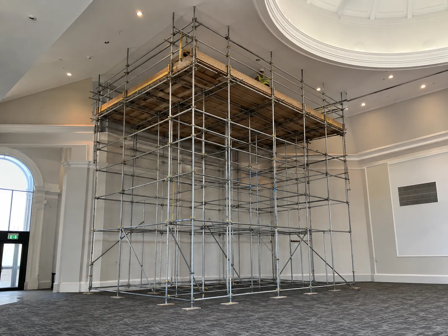 An Ainscaff contractor conducting a site survey at a residential property to plan scaffolding access around a garden conservatory and side gate.