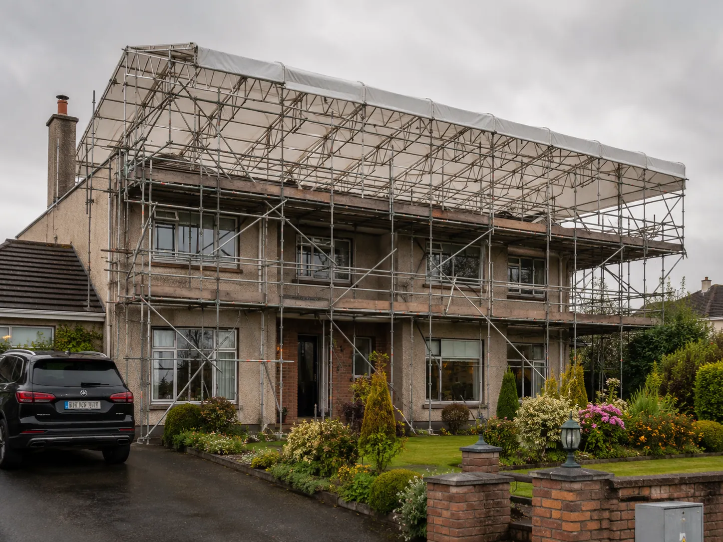 Weather protection scaffolding erected over an occupied domestic property to prevent water from entering living spaces during extensive roof construction.